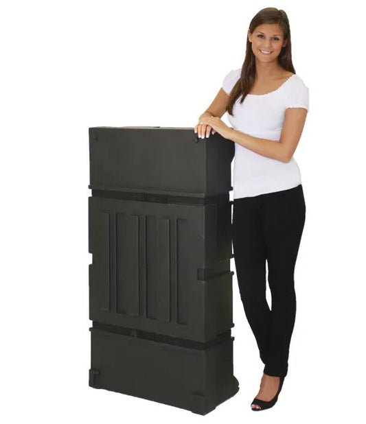 A large, black, rectangular, wheeled display case shown next to a young woman for size comparison.  The case appears to be made of molded plastic and has a handle on one side