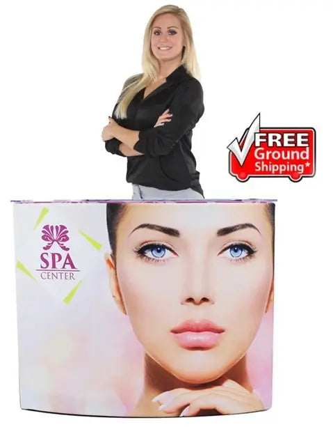 A portable counter with a graphic featuring a woman's face and the "SPA CENTER" logo, with a woman standing behind it and a "Free Ground Shipping" badge in the corner. - Iconic Displays
